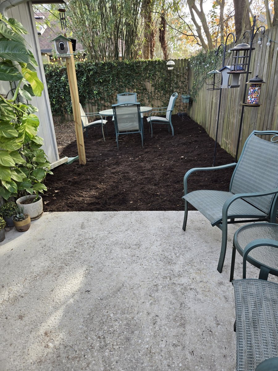 A tidy side-yard patio with a fresh mulch bed